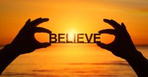 a person holding up a small sign saying believe