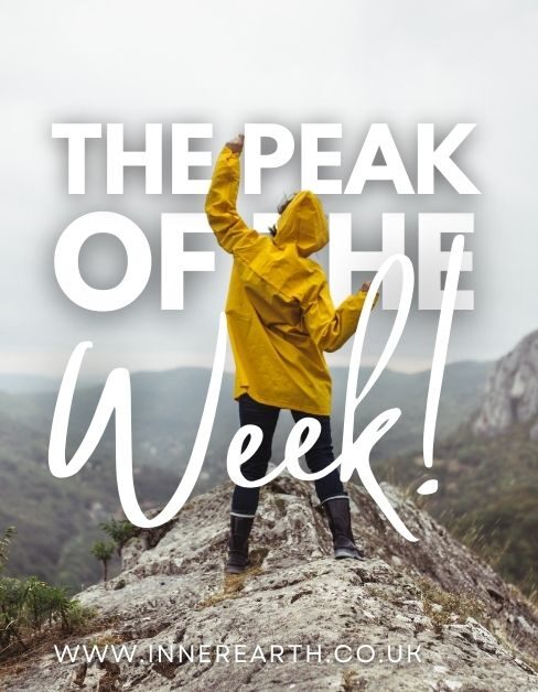 a person in a yellow jacket standing on a peak